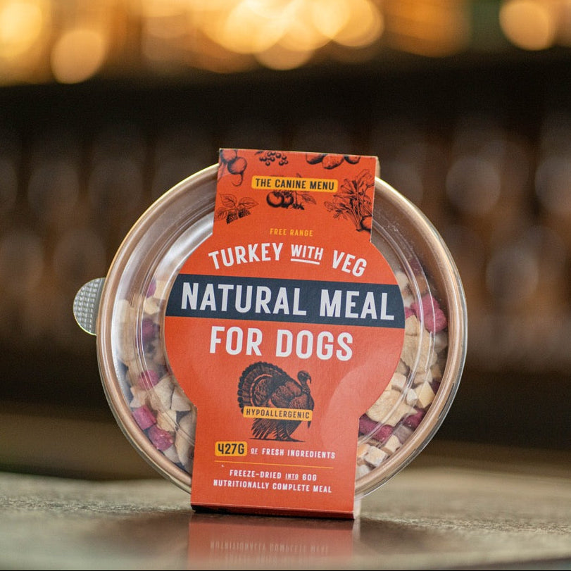 Pet food packaging with 'Natural Meal for Dogs' label on a blurred background